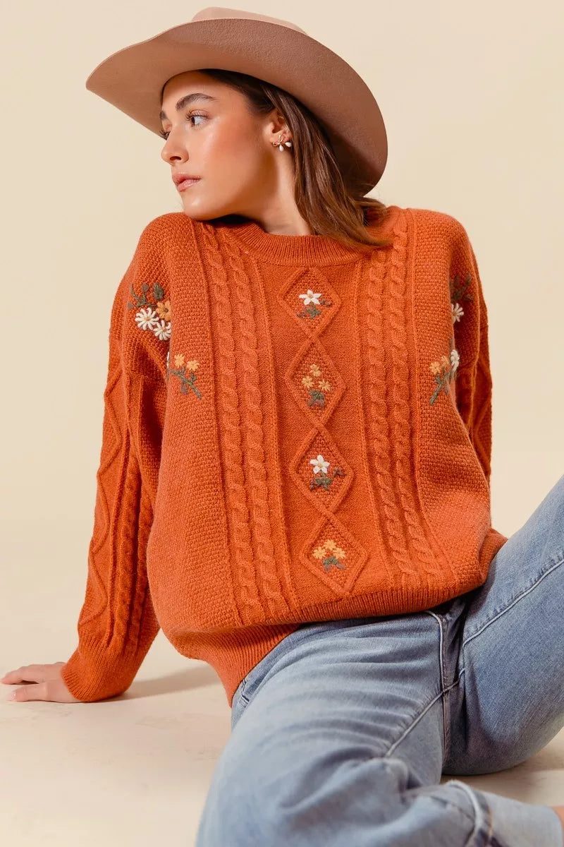 Terracotta knit pullover with embroidered flowers and cable detailing, soft mid-hip length fall sweater