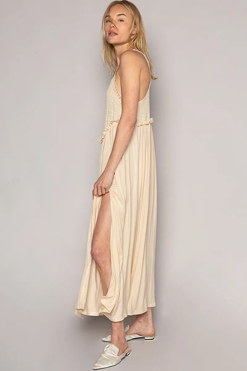 Side view of POL Saltwater Siren Maxi in cream rayon jersey with lace straps, frill waist, and thigh-high slit—paired with neutral flats for effortless beach style.