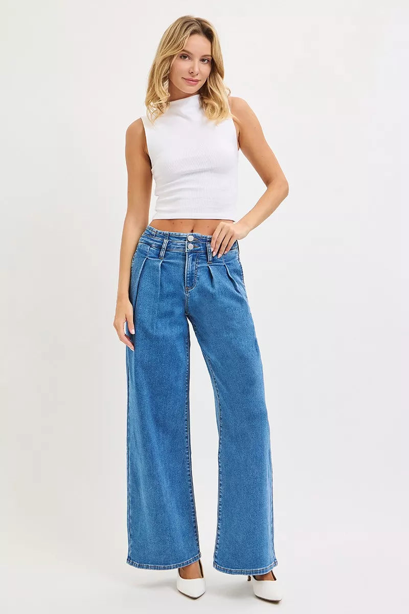 Model in white crop top and heels wearing Risen mid rise wide leg pleated jeans, full front view