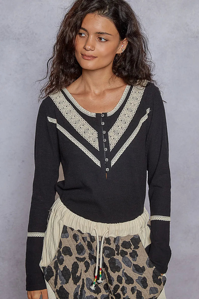 Black rib knit long sleeve Henley top with cream lace trim along the V-neckline, yoke, and bust, paired with leopard print pants. Full front view on a clean backdrop.