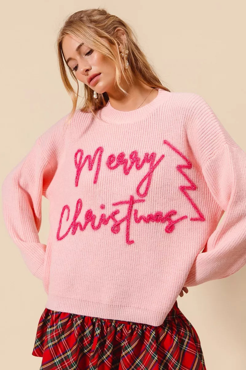 Pink tinsel Merry Christmas sweater with bold lettering, festive women’s holiday pullover knit with long sleeves and ribbed texture