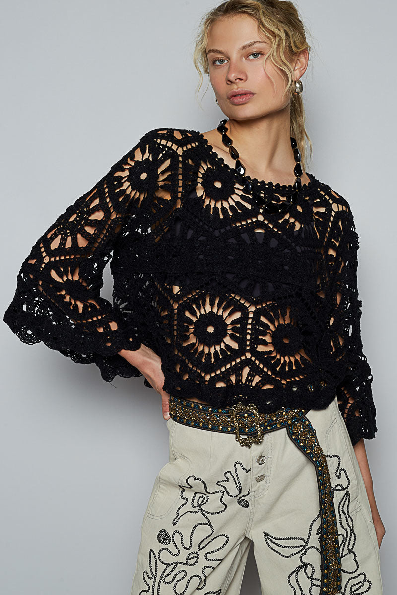 Woman wearing high-waisted cream trousers with black floral embroidery and a multicolor beaded belt; paired with a black crochet top featuring circular lace motifs and scalloped edges; styled for a boho-western look with artisanal textures and elevated casual flair; evokes festival-ready fashion and handcrafted statement dressing.