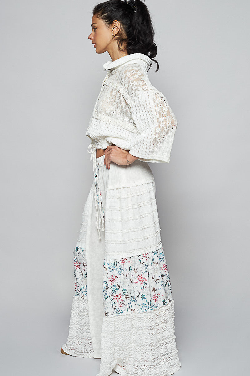 Side profile studio shot of a woman wearing a white lace top and Sunspell Flares, highlighting the full silhouette of the wide, flared leg and side details of the floral lace patchwork.