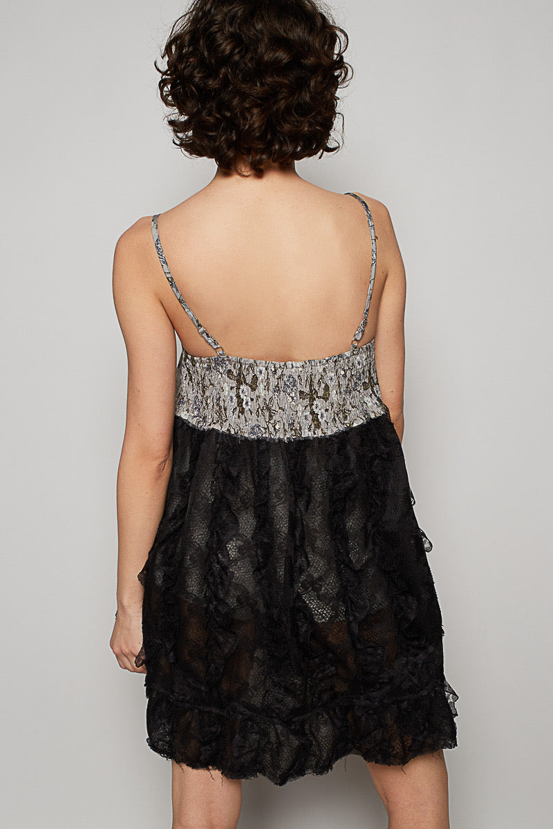 Back view of black babydoll mini with semi-sheer lace skirt, 3D ruffle trim, and adjustable spaghetti straps against a plain background