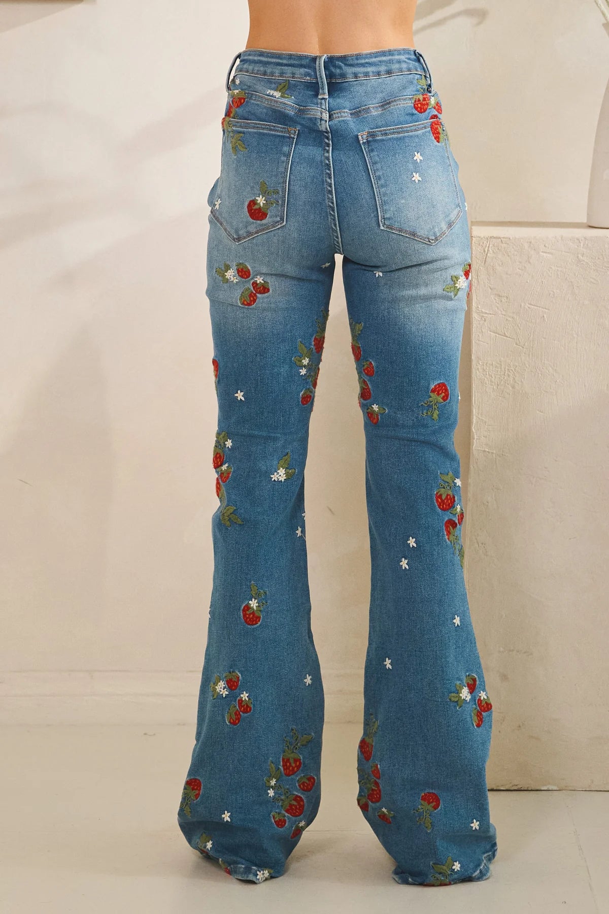 Embroidered flare jeans by Oli & Hali in dark denim with strawberry embroidery showing rear pockets and a high waist
