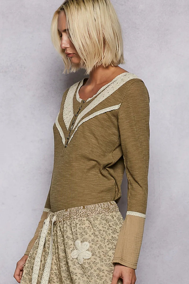 Side view of model in an olive rib knit top with cream lace trim on yoke & bust, long sleeves with contrast cuffs on a clean background