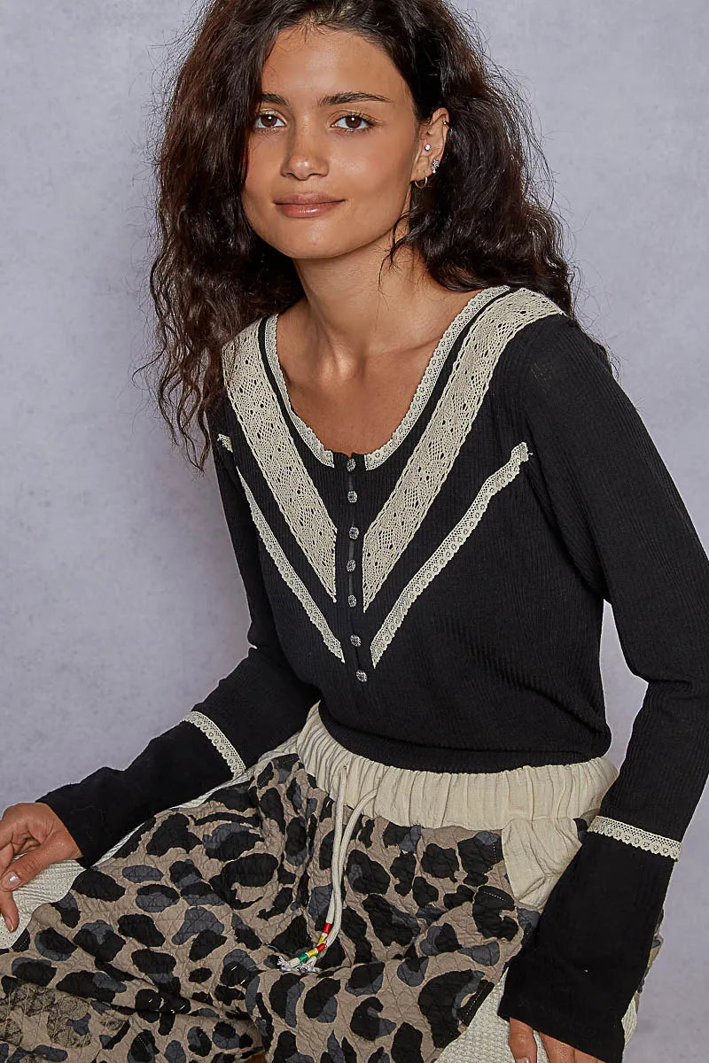 Black rib knit regular fit long sleeve Henley top with a V-neckline and cream lace trim, paired with leopard print pants on a clean backdrop.