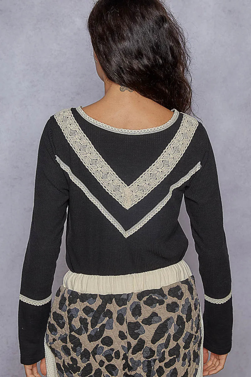 Back view of black rib knit long sleeve Henley top featuring lace trim along the neckline, yoke, and mid-back, worn with leopard print pants on a plain background.
