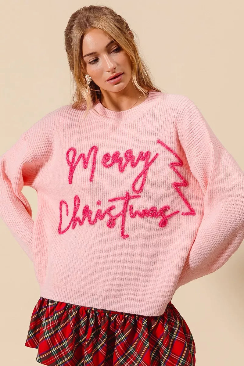 Women’s pink Christmas sweater featuring tinsel lettering and zigzag tree design, cozy holiday pullover for cheerful winter outfits