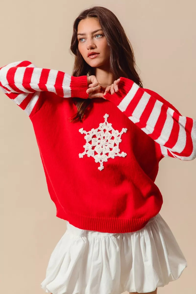 Red knit sweater with white striped sleeves and crochet snowflake patch styled with mini skirt for holiday look