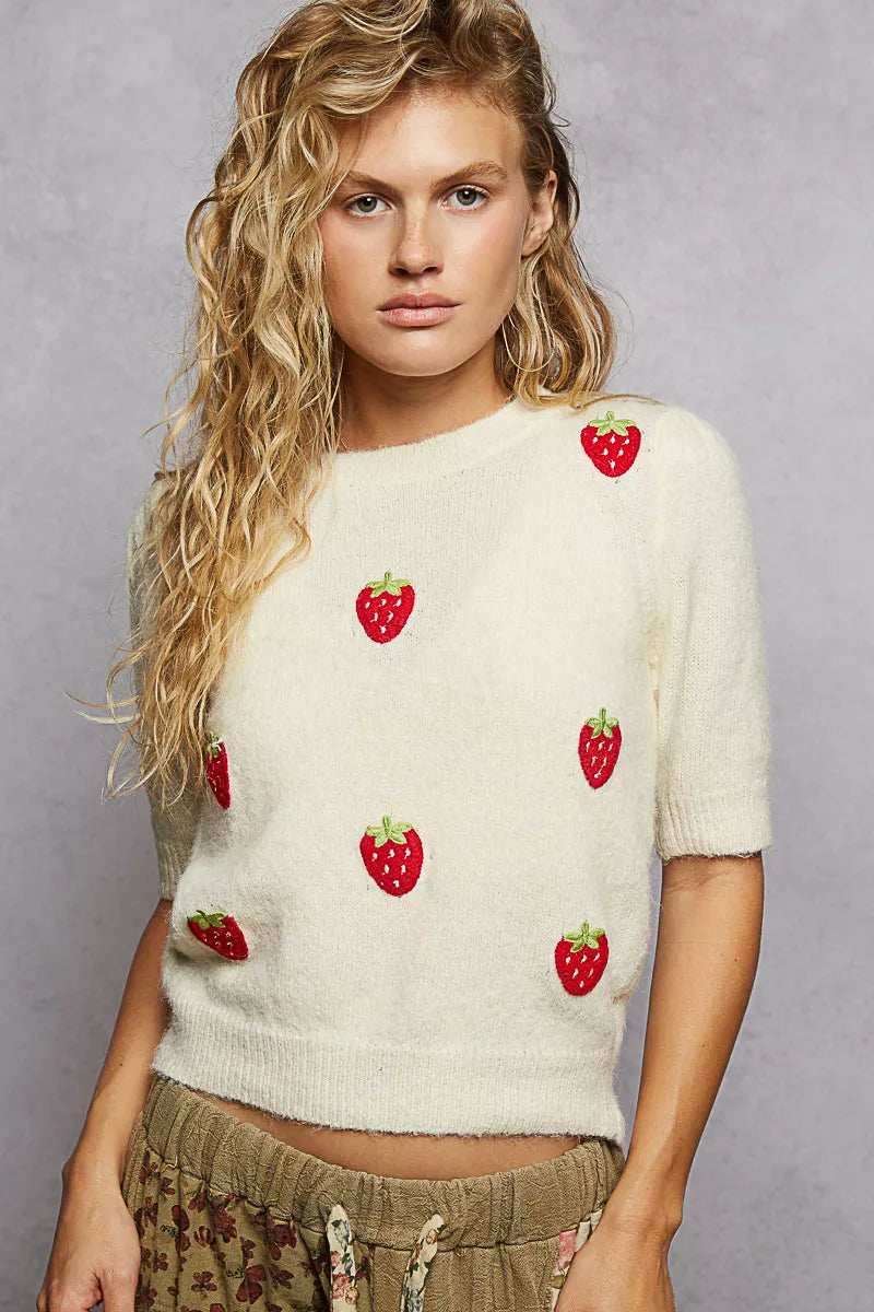 Cropped cream knit sweater with embroidered red strawberries, ribbed knit edges and a relaxed fit