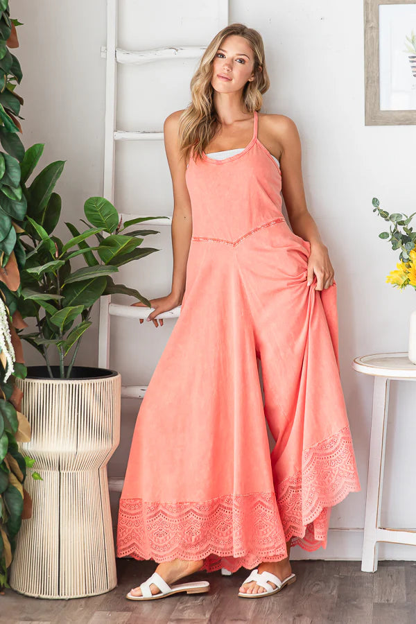 Coral cotton jumpsuit with lace trim and wide legs, styled on a model in a relaxed boho studio setting.