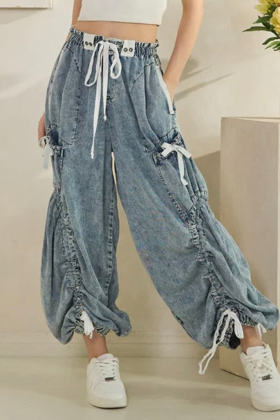 Cropped view of a woman wearing Oli & Hali cinched jogger jeans with a drawstring waist, styled for boho streetwear; fashion-forward denim featuring relaxed fit and urban flair. trendy casual outfit
