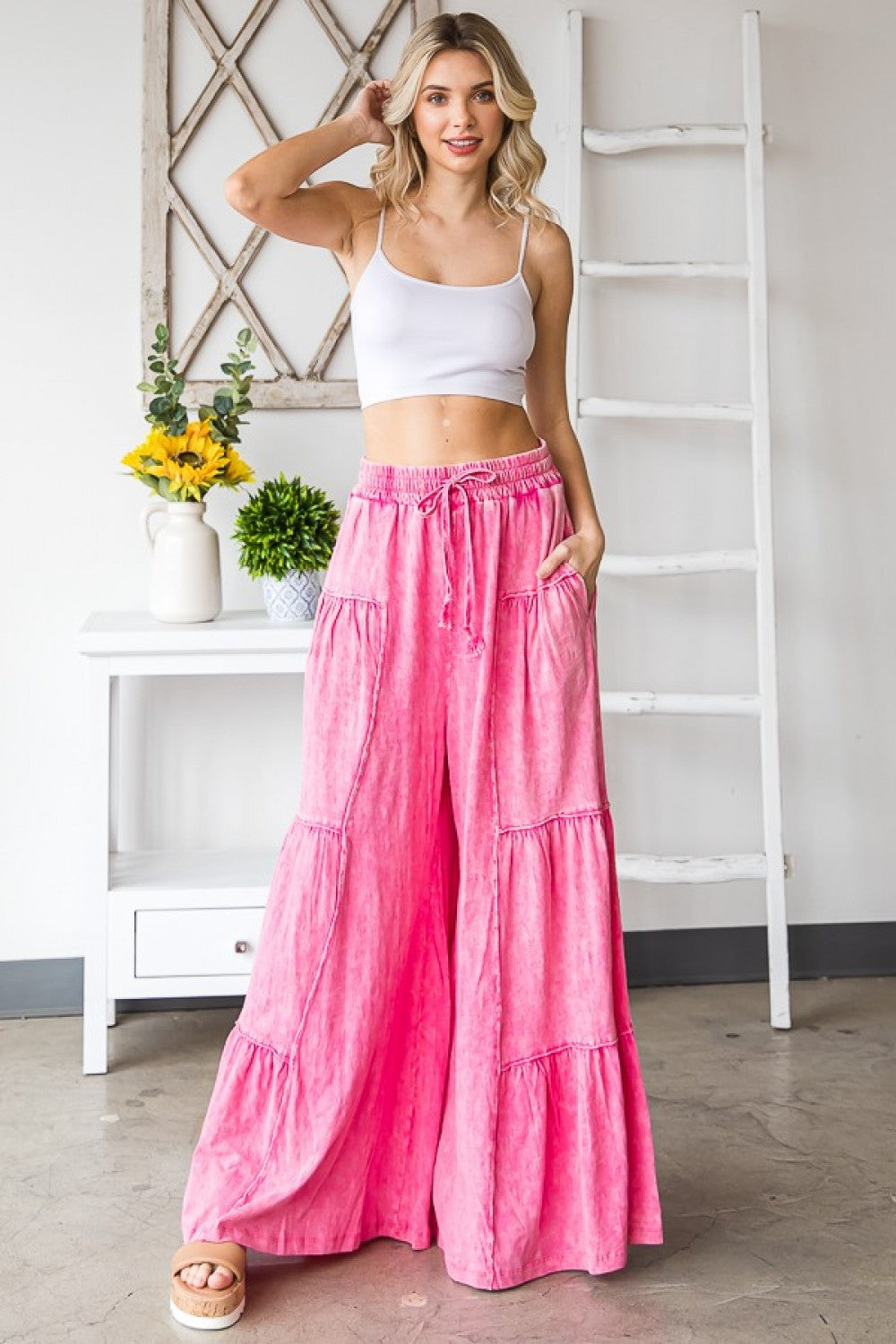 Hot Pink Mineral Washed Wide Leg Tiered Cotton Pants. They have an elastic waistband with a drawstring. There are Ruffle details on each tier. The pants are flowy, loose fitting and comfortable