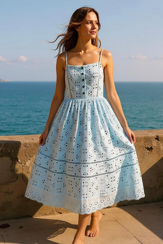 Sky blue cotton eyelet sundress with a midi silhouette, decorative front buttons, and adjustable straps. Displayed against a neutral background, the dress highlights breezy resortwear styling and intricate embroidery details—perfect for summer travel, Mediterranean-inspired fashion, and vacation-ready wardrobes.
