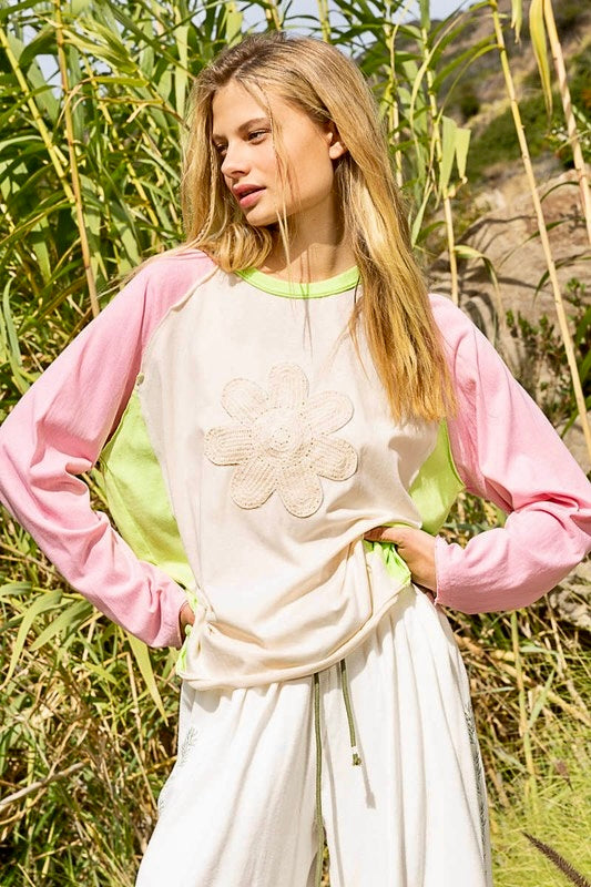Cream cotton/poly jersey top with pink long sleeves and lime green color blocked sides and neck band. It has a cotton daisy flower patch on center front. The top has a relaxed, comfy fit with a longer length. It’s stylish, fun, and trendy with a boho vibe.