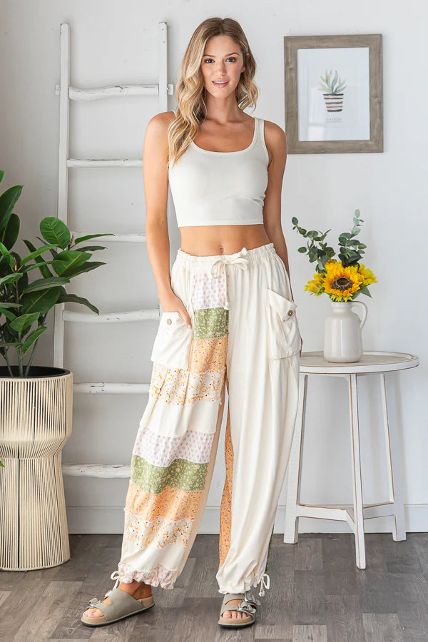 Full-length studio shot of a woman wearing the Shore Thing Pants in cream patchwork, showcasing the loose jogger fit and a relaxed, boho style.