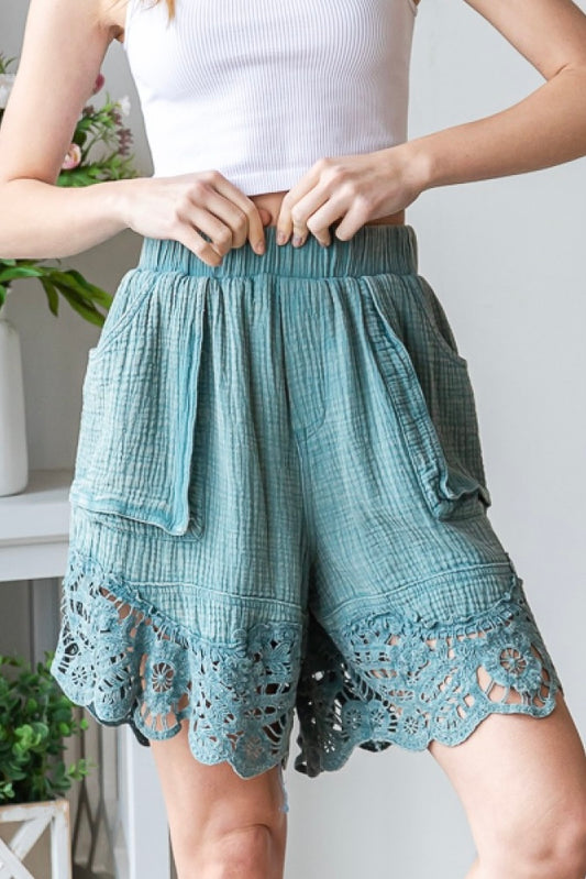 Mineral washed cotton shorts with a wide elastic waist band and pouch pockets. The shorts have a relaxed, loose, comfortable fit with a longer length for more coverage. They are finished with a lace bottom hemline and come is 2 colors - teal and terracotta. The shorts have a casual, boho, beachy vibe.
