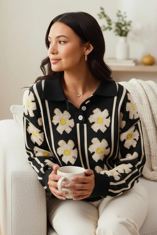 Black floral polo sweater with ivory daisies, in a cozy living room while holding a coffee mug