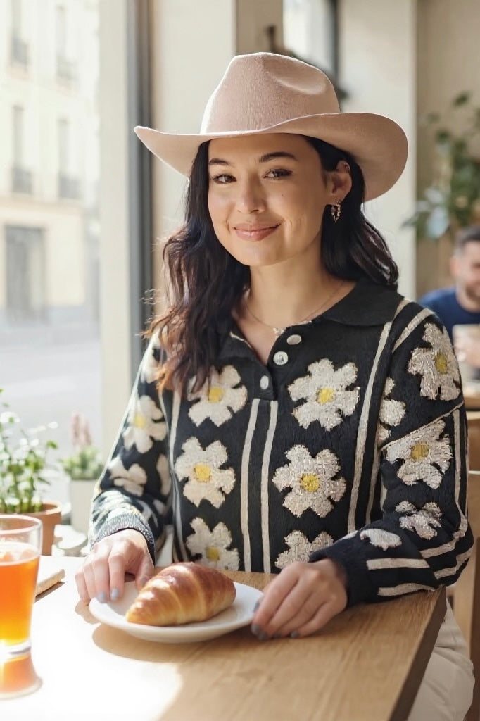 Black polo collar sweater with ivory daisy flowers, styled at café table with croissant and drink