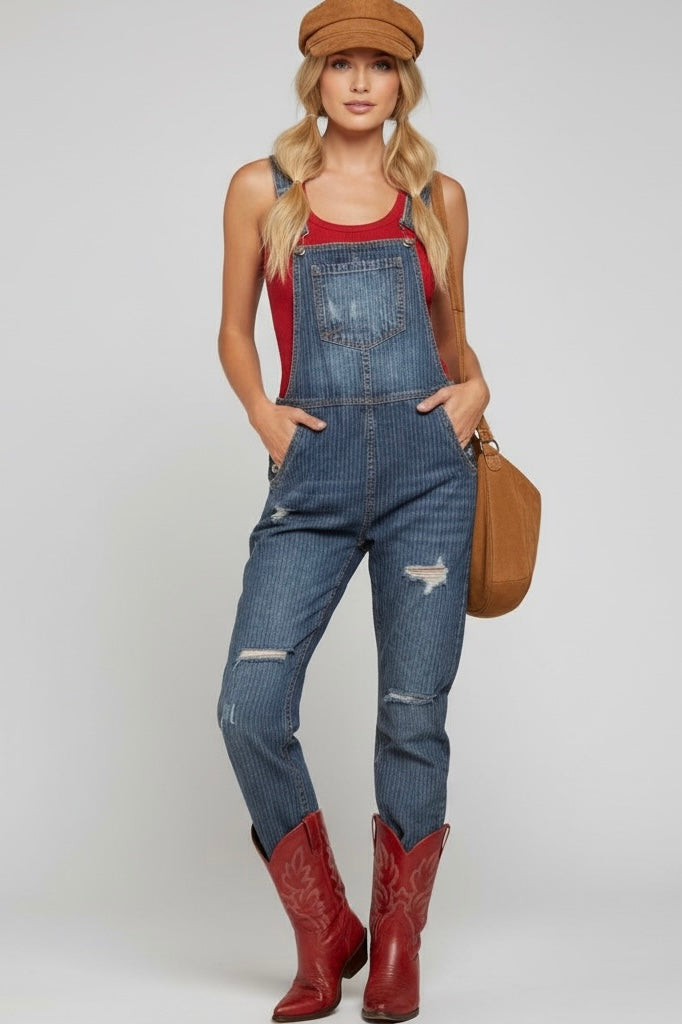 Pinstripe dark wash denim overalls with distressed details, fitted fit, cropped ankle and adjustable straps styled a hat and cowboy boots