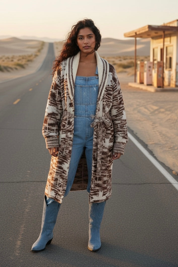 Southwestern geometric belted long sweater cardigan styled with denim overalls and blue boots on a desert highway road trip
