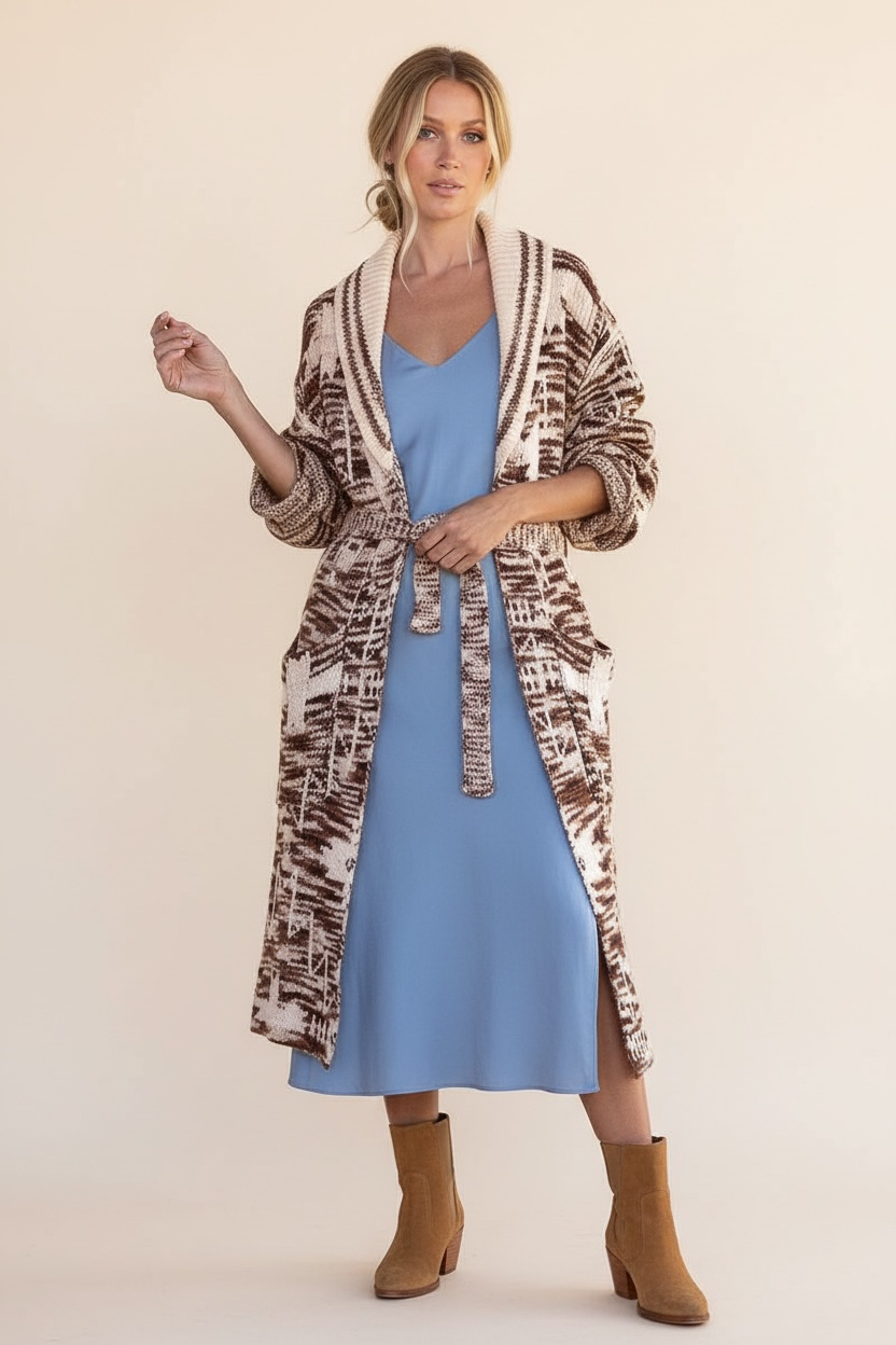 Brown and beige belted long knit cardigan styled over a blue midi dress with tan ankle boots for a travel outfit