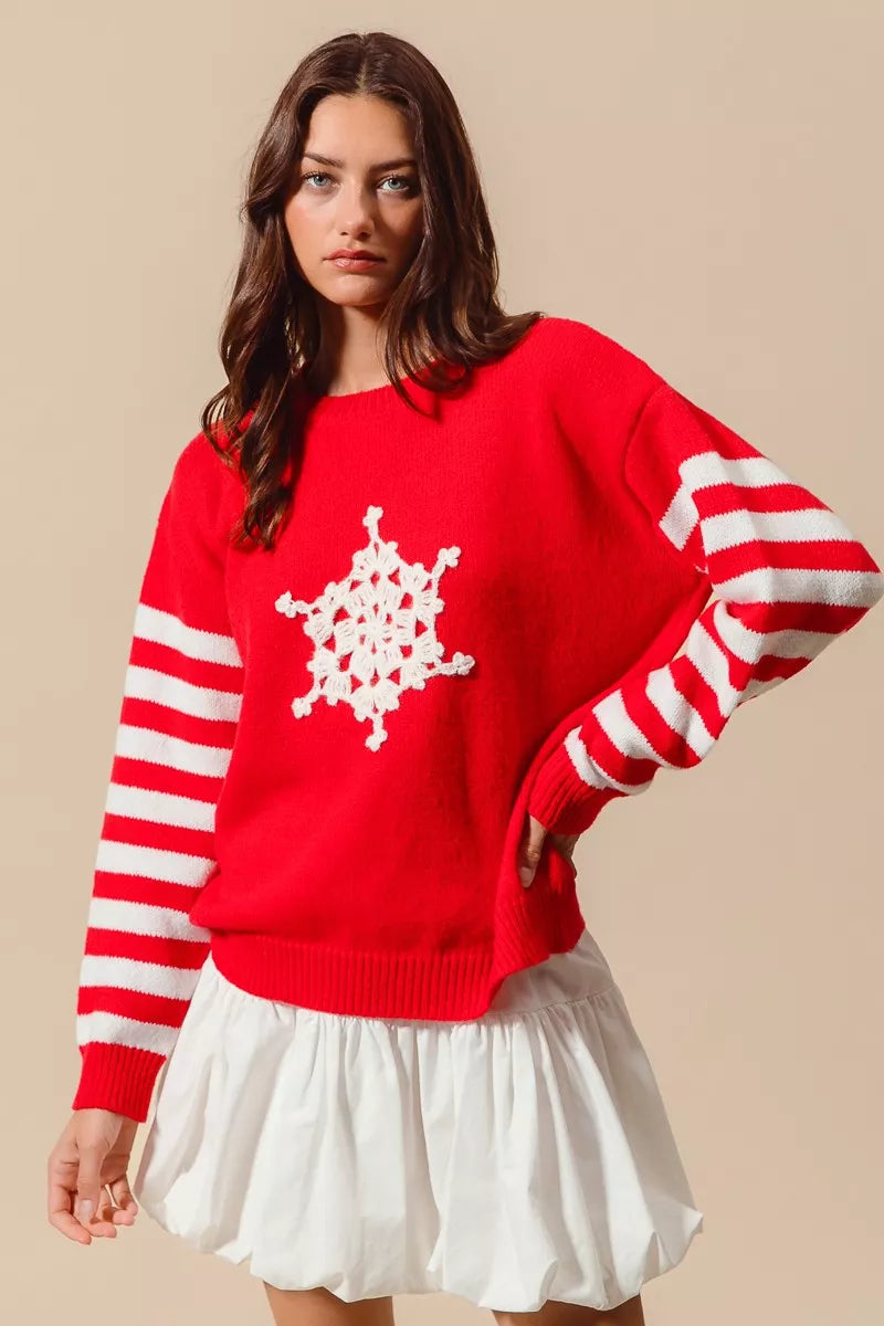 Red Christmas sweater with striped sleeves and crochet snowflake detail paired with white skirt for playful style