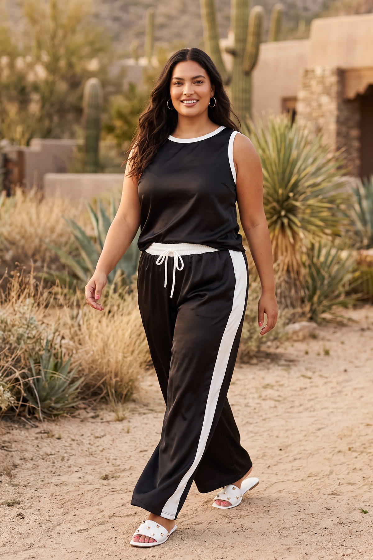 Black wide leg pants set with white side stripe and trimmed tank walking forward on a desert path