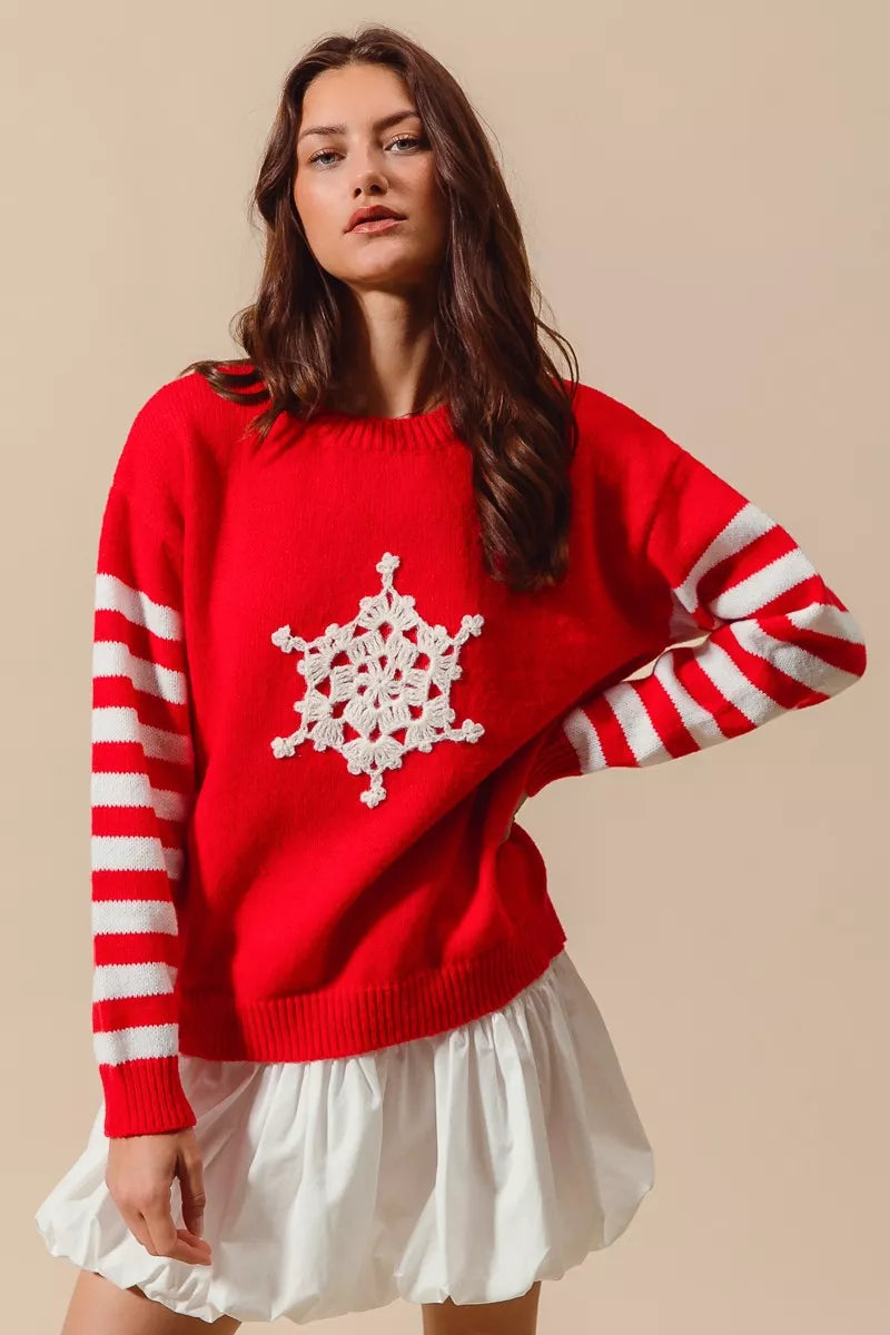 Red slouchy sweater with white striped sleeves and crochet snowflake patch styled with mini skirt for festive holiday look