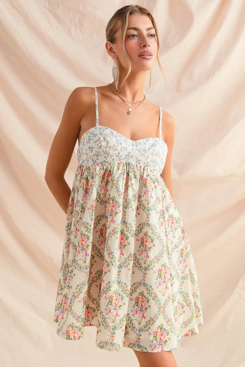 Woman in sleeveless floral cami mini dress with sweetheart neckline and flared skirt, styled softly against neutral backdrop