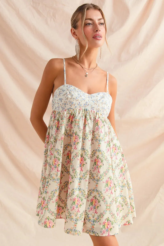 Woman in sleeveless floral cami mini dress with sweetheart neckline and flared skirt, styled softly against neutral backdrop