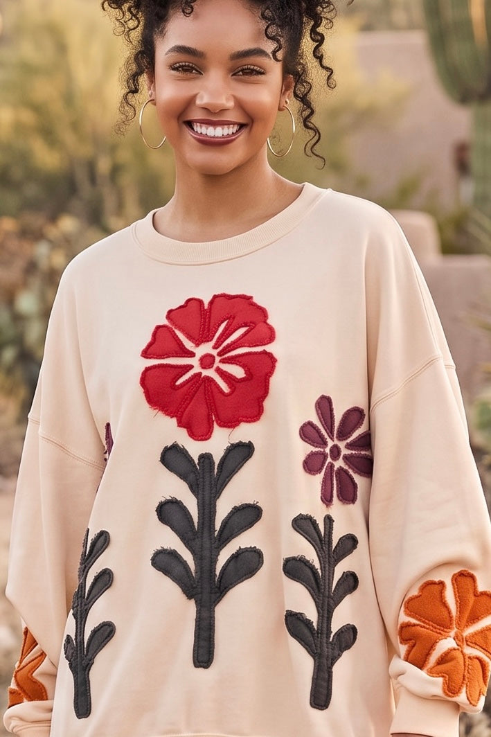 Red wildflower appliqué close up stitched on a cotton french terry top with plum flower and stems