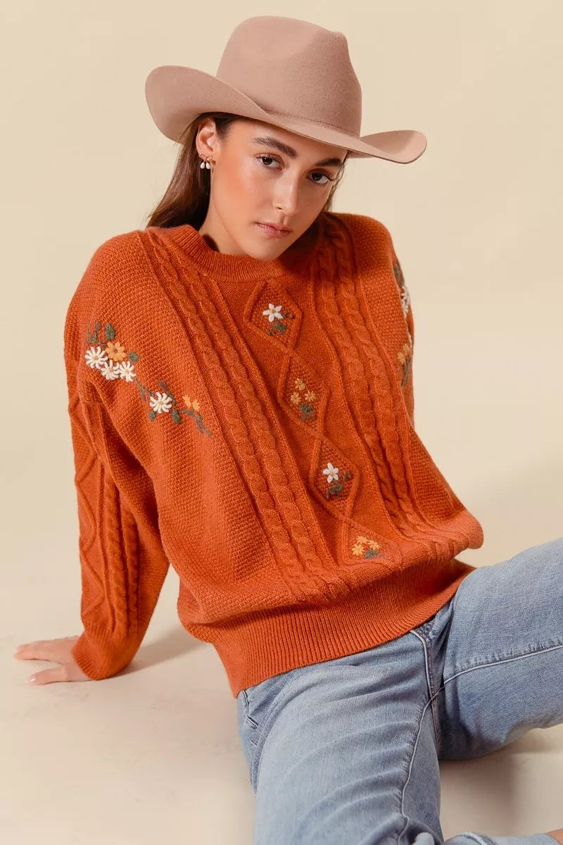 Burnt orange cable knit sweater featuring floral embroidery and vintage diamond pattern for romantic boho layers