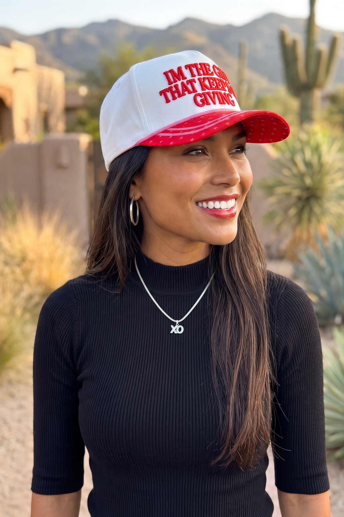 Holiday trucker hat in 3/4 side profile with bold red lettering and a red brim covered in pink stars