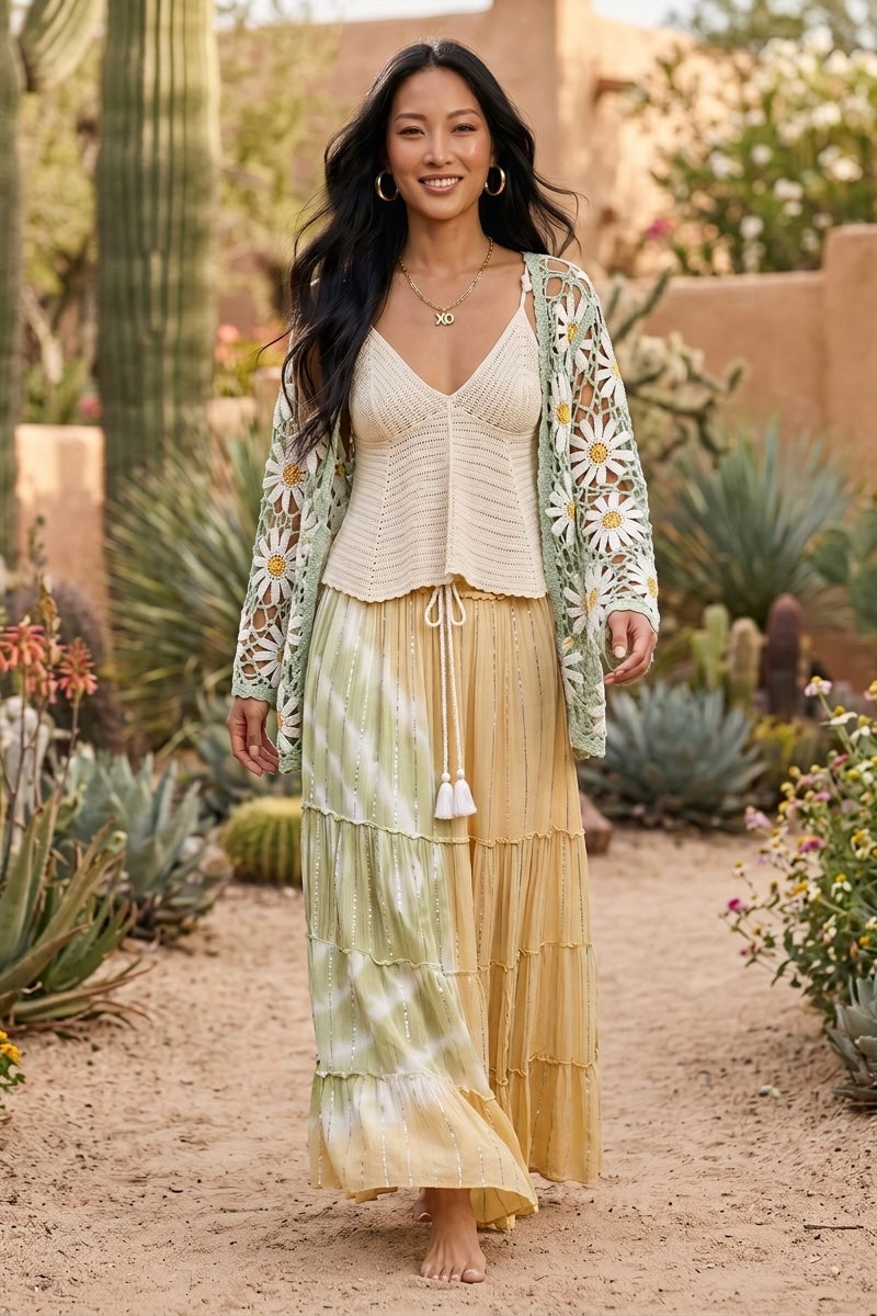 Tiered tie dye maxi skirt with tassel tie paired with a green daisy crochet cardigan among cacti