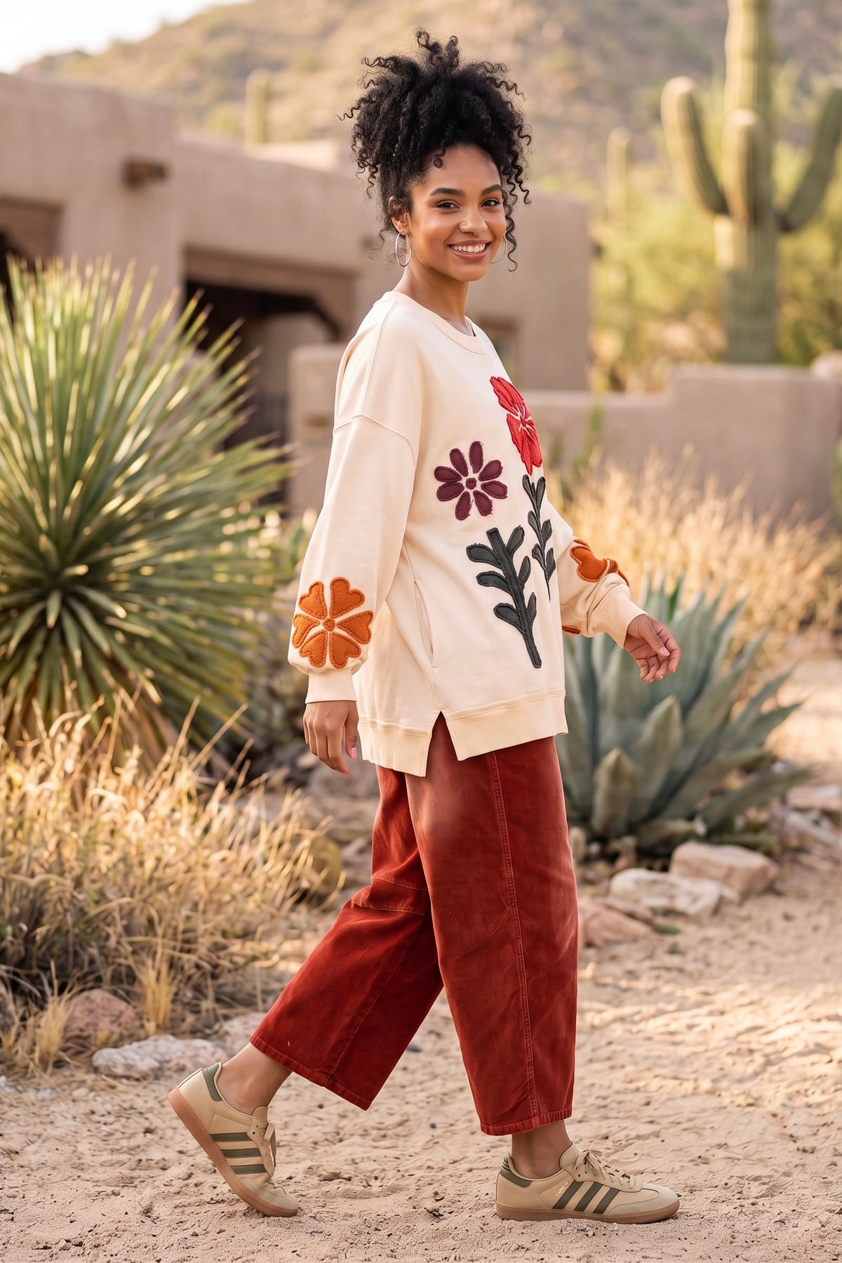 Ivory cotton sweatshirt walking with purple flower, olive stems, and orange sleeve blooms desert outdoors